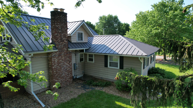grey house with metal roofing and brick chimney bourbon in